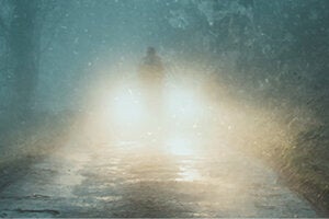 blurry figure in front of car headlights