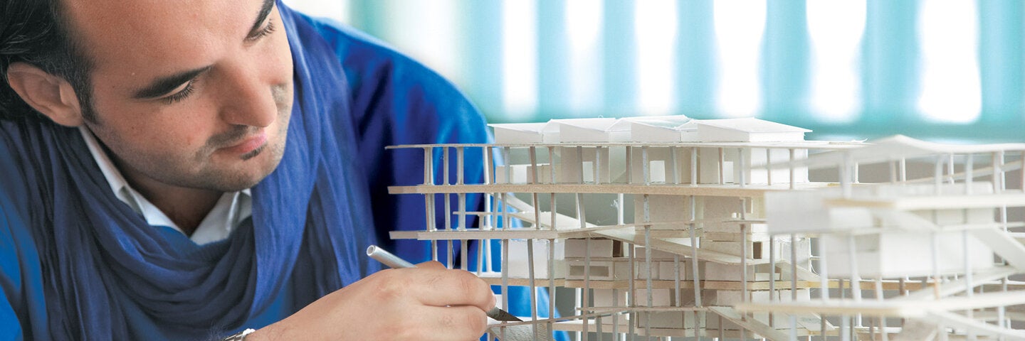 Male architecture student making a model of a building.