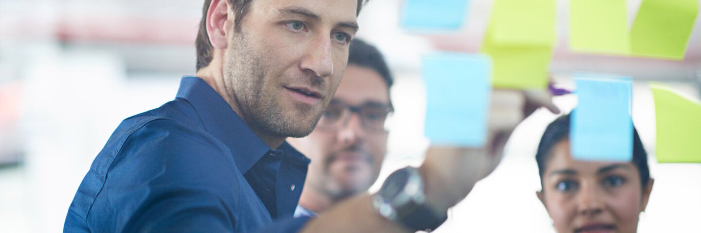 professional working with arranging sticky notes on a glass wall