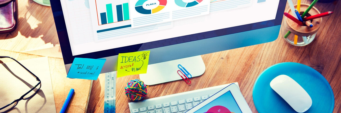 Businessman looking at analytics on a tablet and monitor