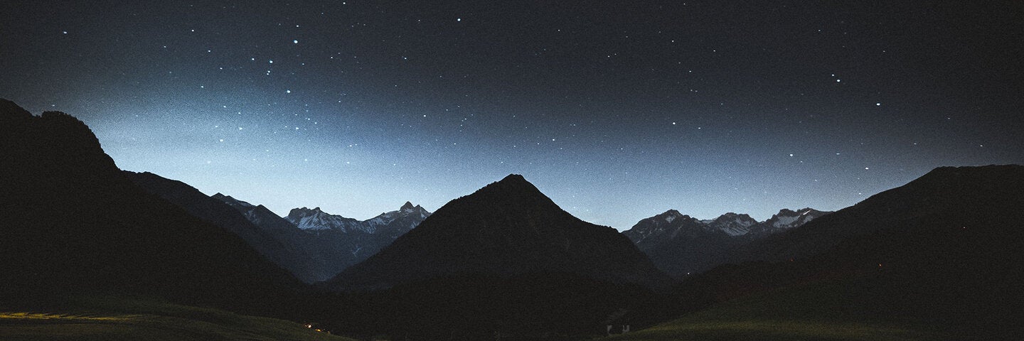 Photo of a mountain range and field at night.