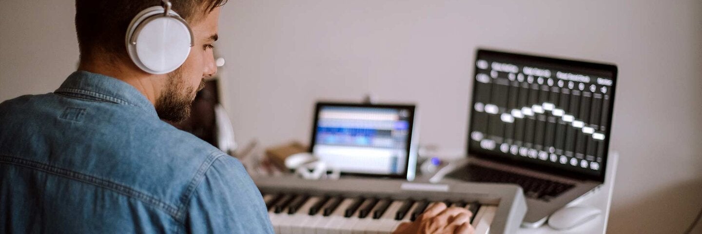 Young Musician Playing Synth And Writing New Composition