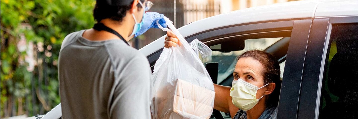 woman picking her restaurant food from her car at a pick up