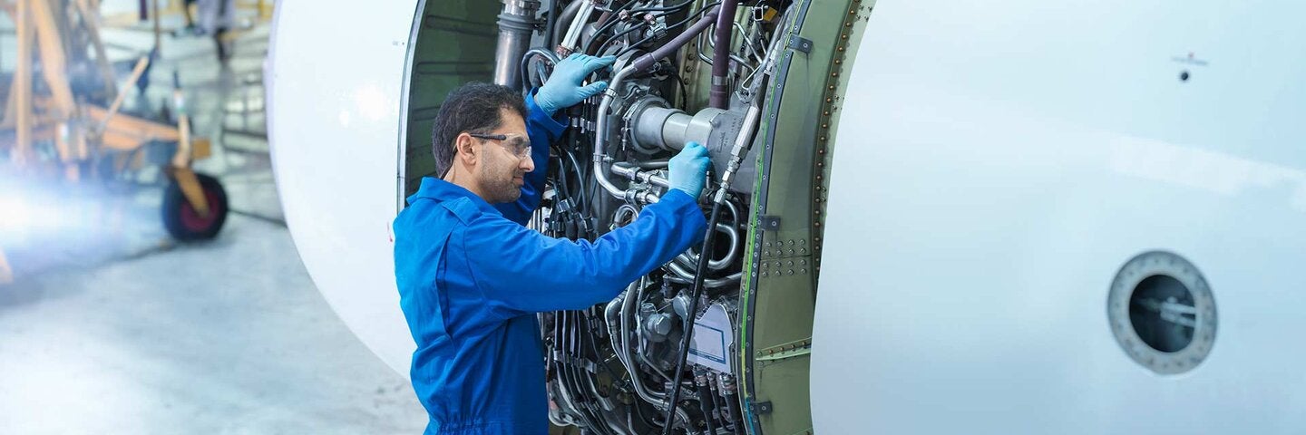 Engineer working on jet engine in aircraft maintenance factory