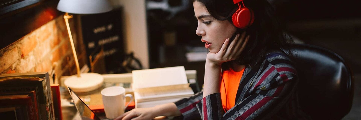 young millennial using laptop while listening to music in her Downtown Los Angeles apartment