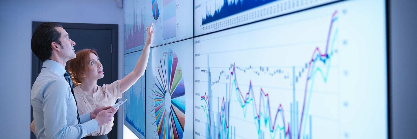 Business colleagues studying graphs on screen in meeting room