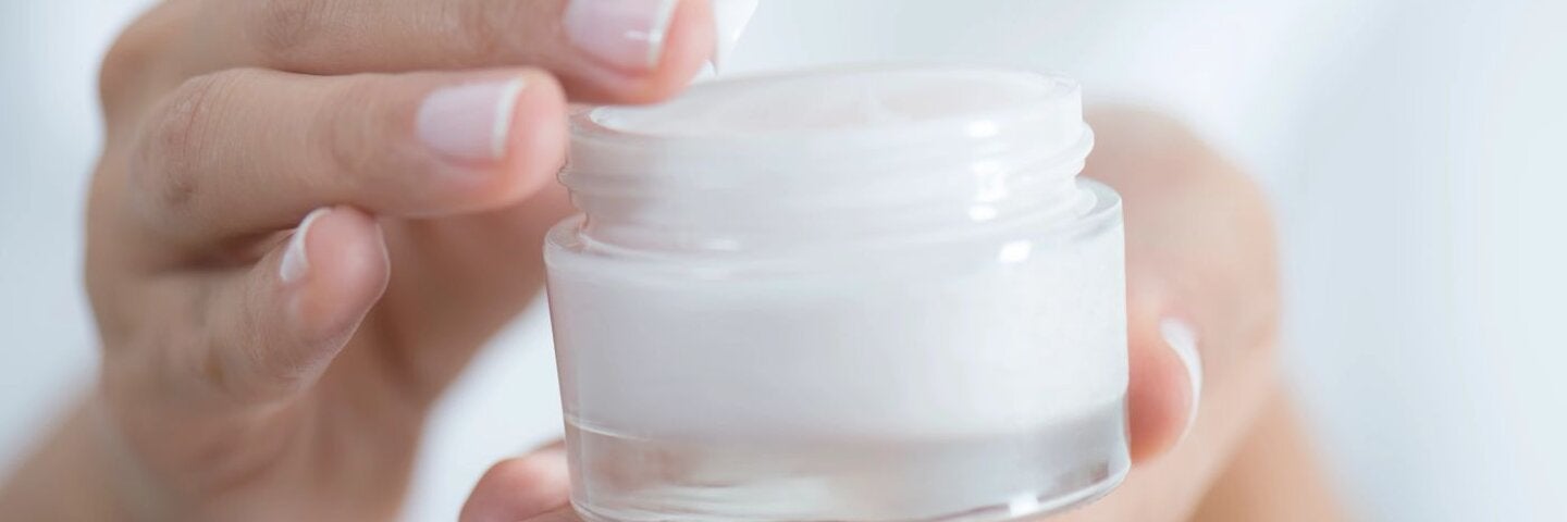 Hands holding a jar of facial cream
